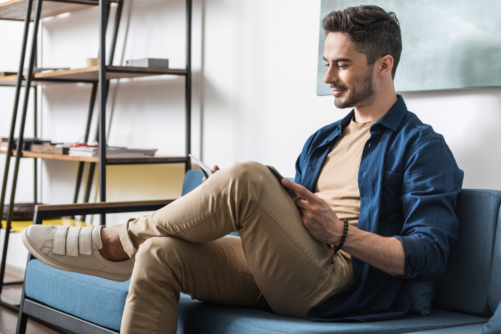 Cheery youthful bearded guy spending spare time inside apartment